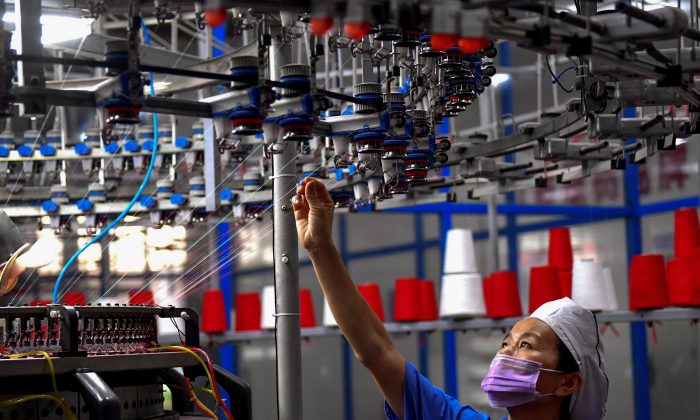 An employee monitors a circular weaving machine at a textile factory in Shangqiu City, Henan Province, China, on Sept. 8, 2018. (STR/AFP/Getty Images)